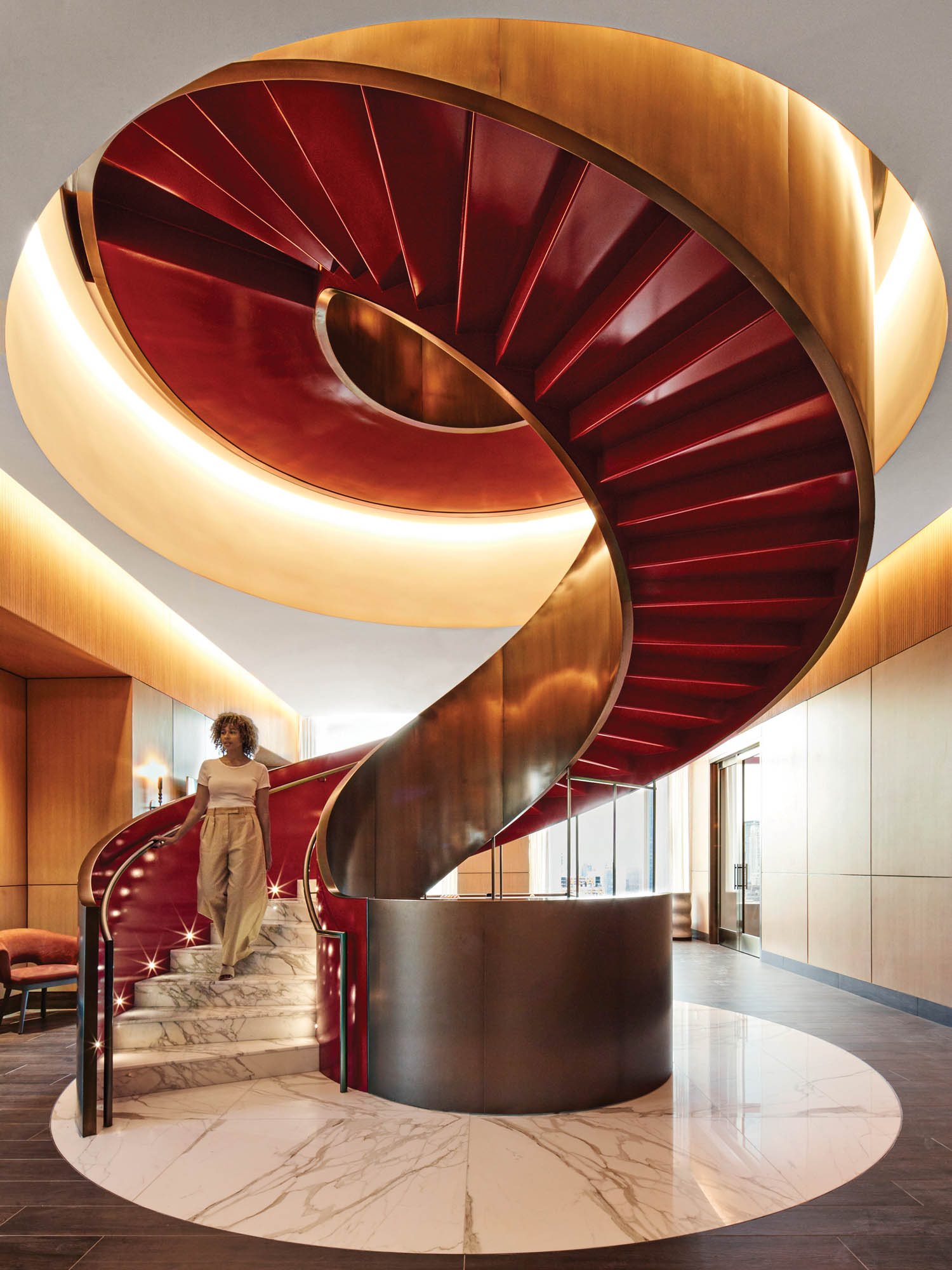 a spiral staircase marble stairs, bronze handrails and glossy red paint