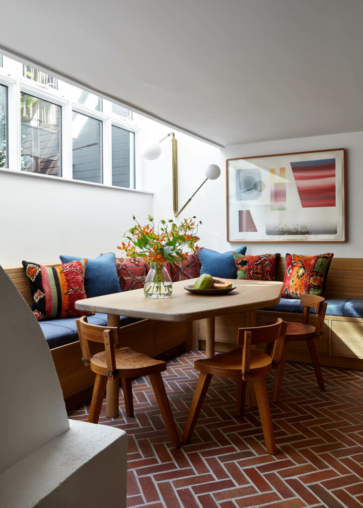 a dining area with brick flooring, banquette seating, and dining chairs