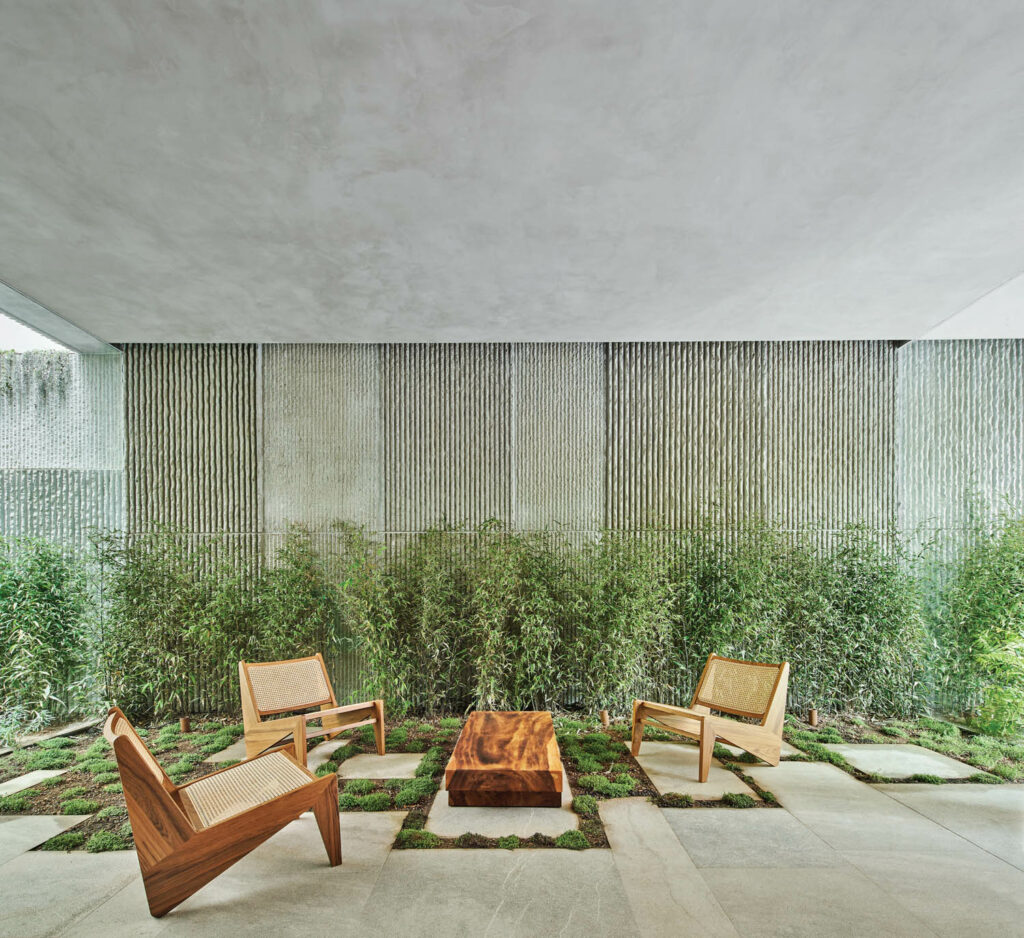 a trio of outdoor arm chairs and a table in front of Spanish cane on the courtyard of an apartment building in Spain