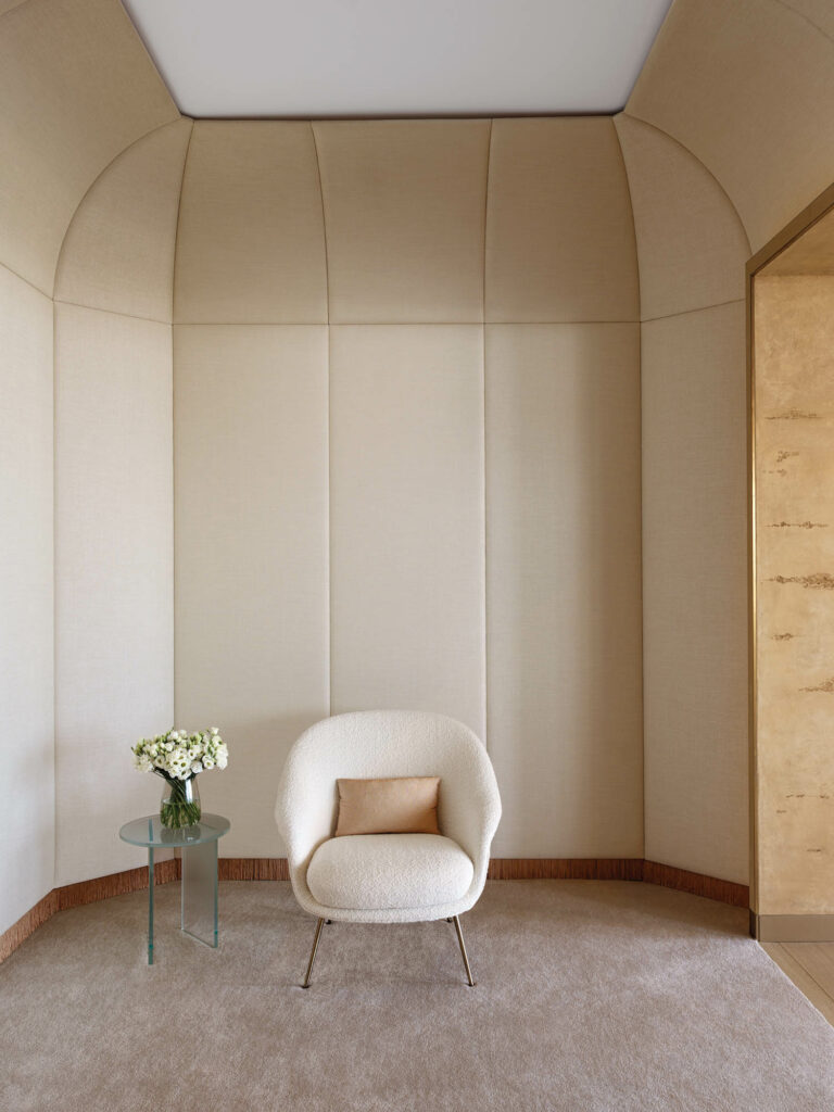 fabric panels encase an entry hall with a lounge chair and a glass table