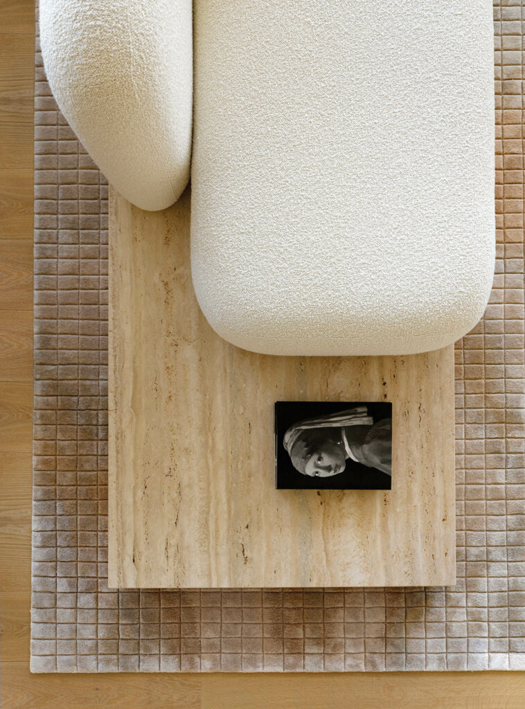 a bouclé-upholstered cushion on a travertine slab in an apartment living room