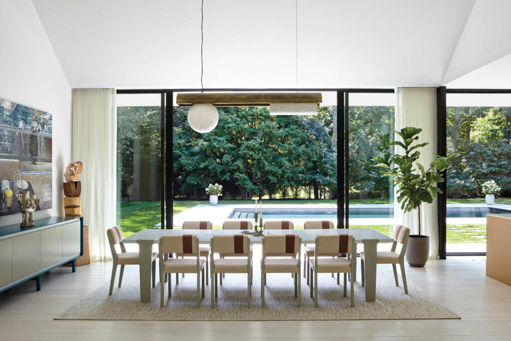 a dining room surrounded by glass walls looks over a pool at this home