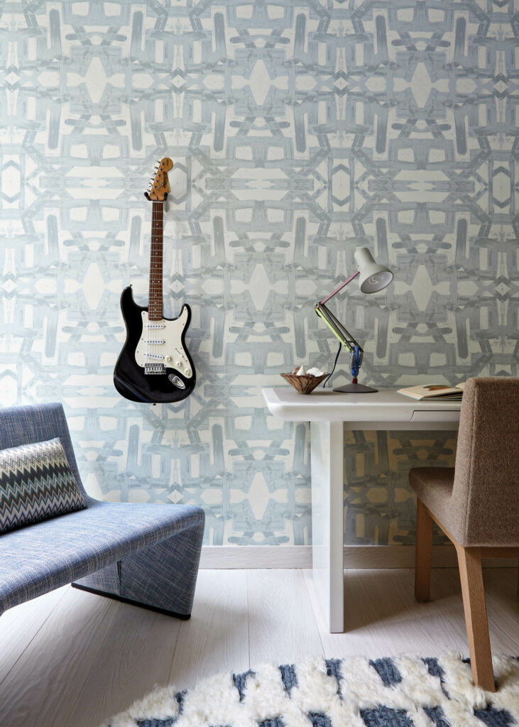 an electric guitar hangs on the wall of this girl's bedroom with a Lindsay Cowles wallcovering behind it