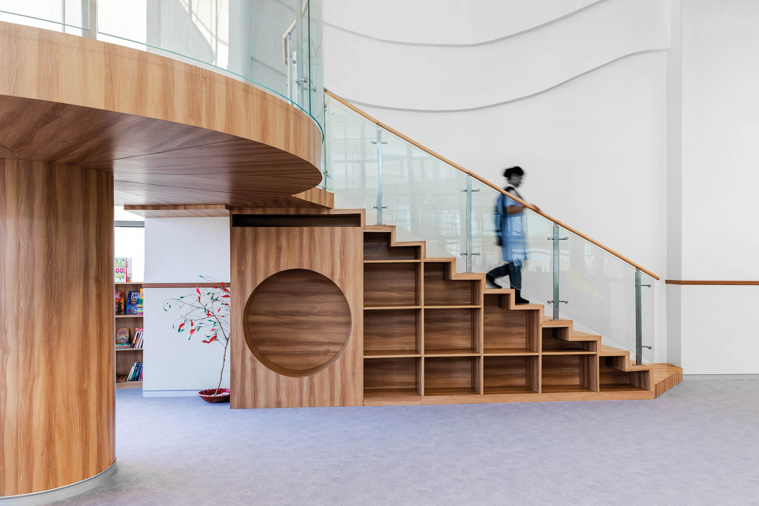 a person walks down stairs above built in shelving in an Indian grammar school