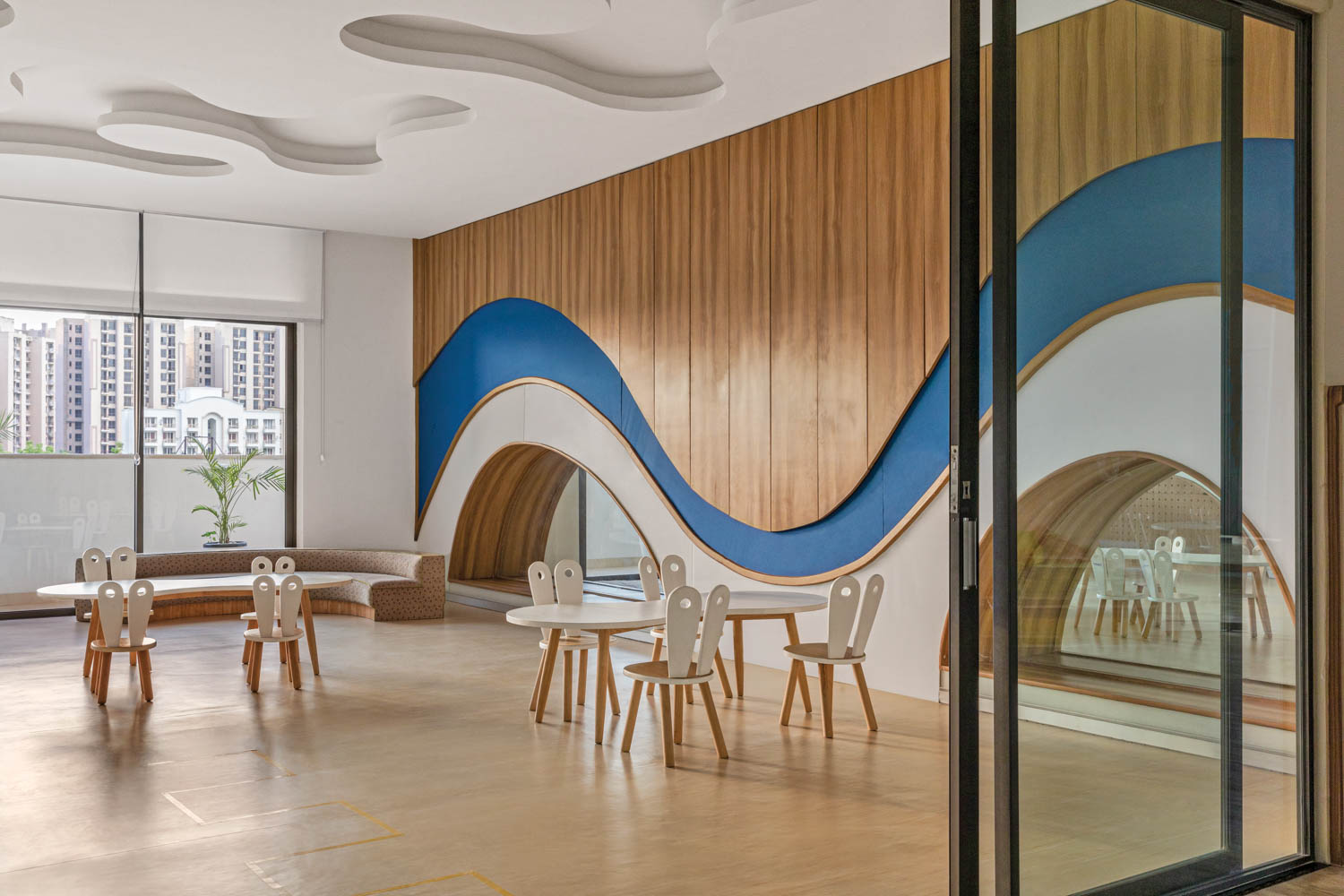 blue, white, and wood paneling curve across a wall in learning room at this grammar school