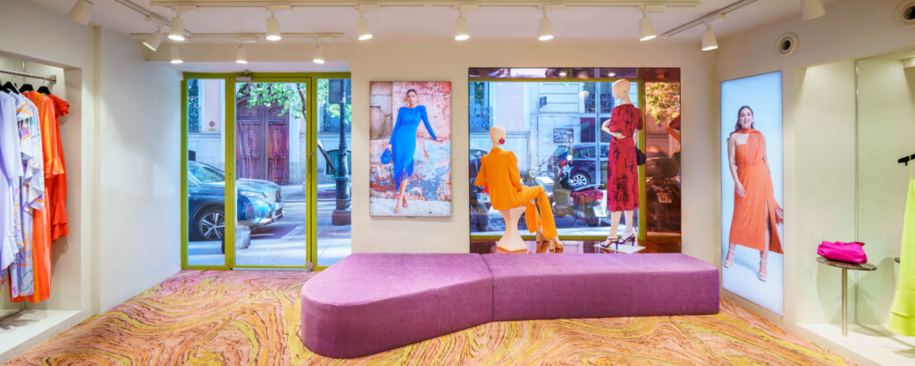 a curvy sofa covered in fuchsia velvet at a retail store