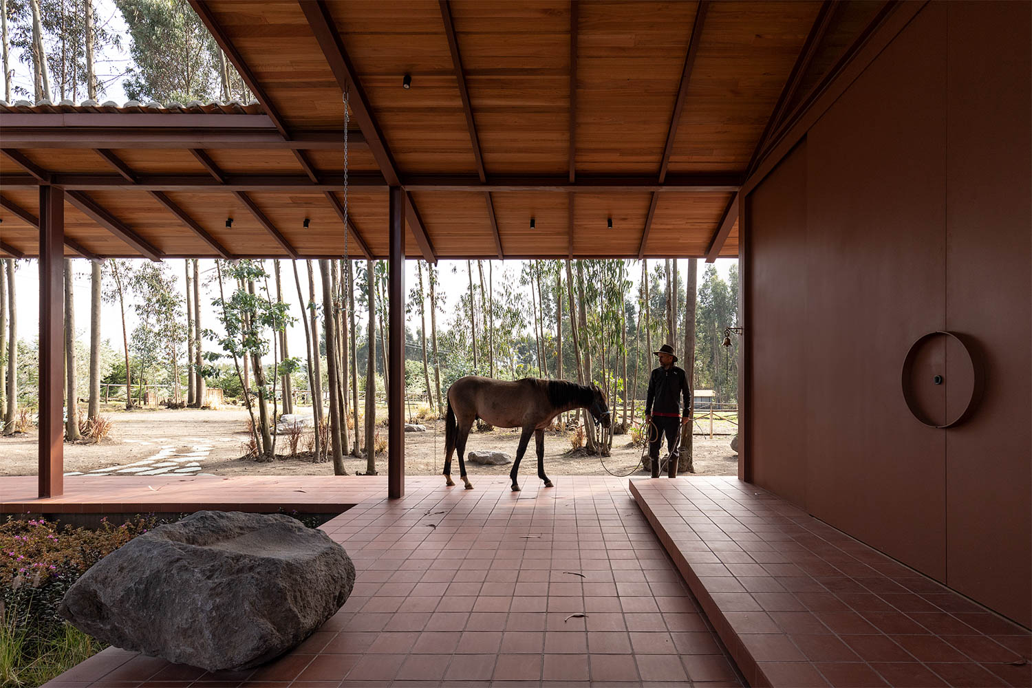 A person walks a horse through a canopied structure