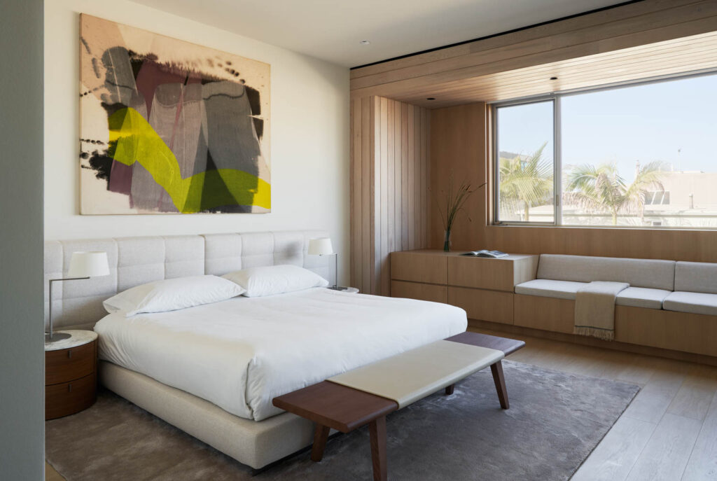 the primary bedroom of a Manhattan Beach house with large windows and an acrylic on canvas painting above the bed