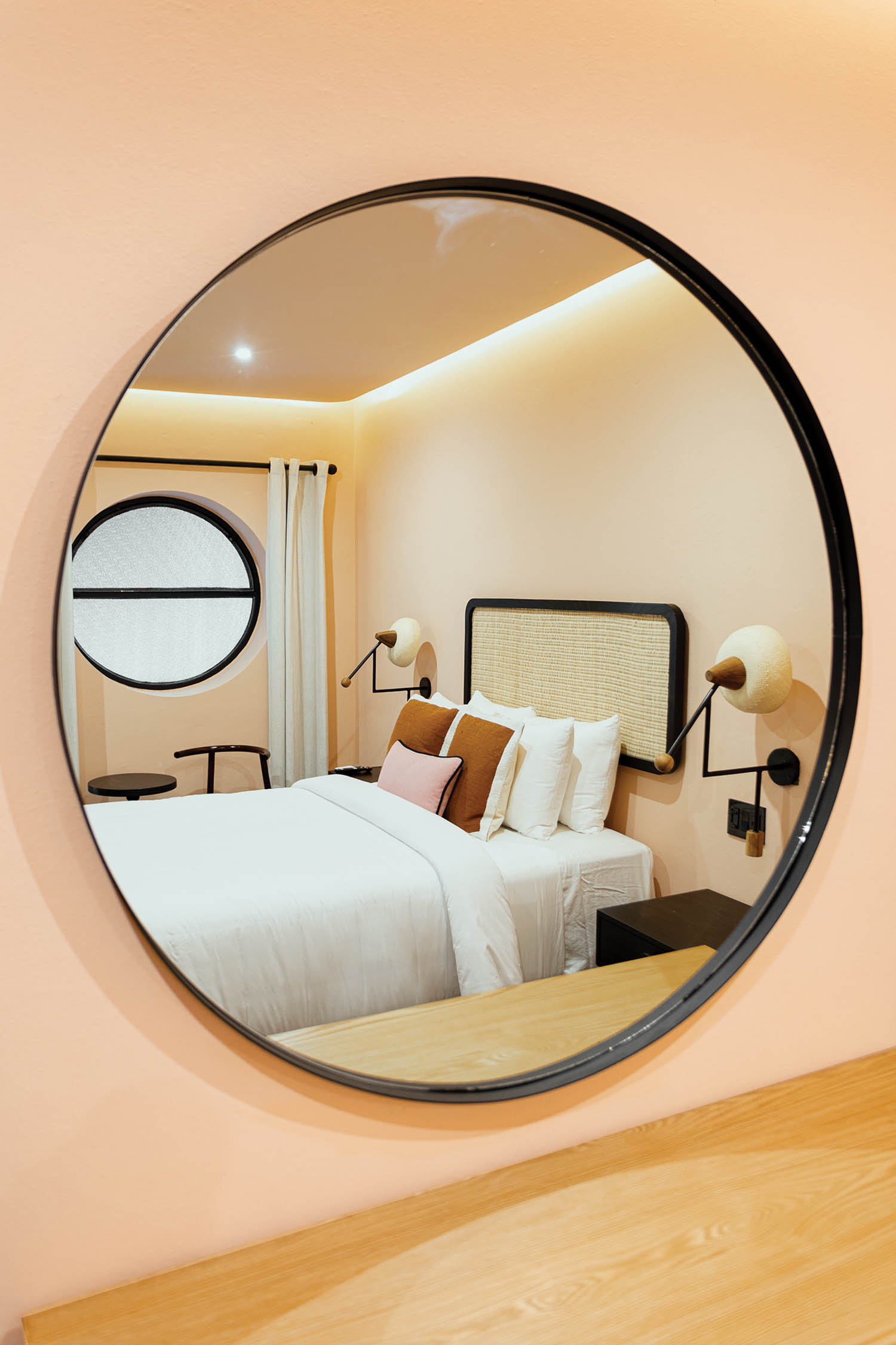 a circular mirror displays a guest bed in this hotel