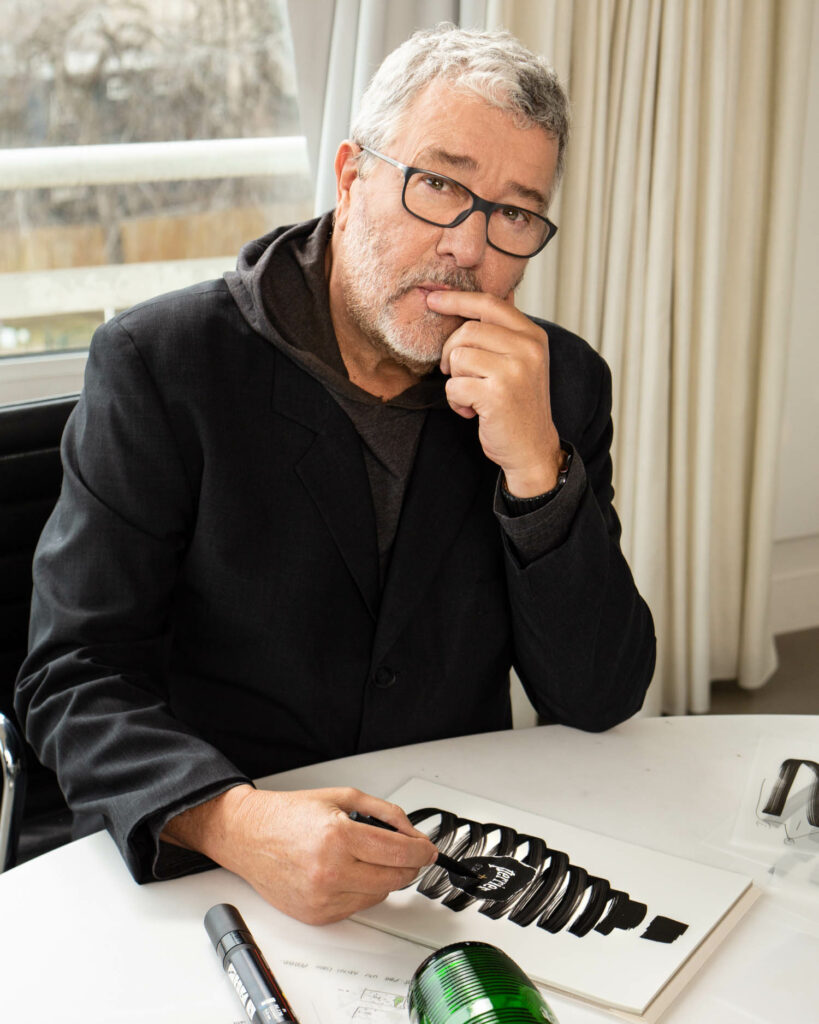 philippe starck in a black sweater drawing with a black marker