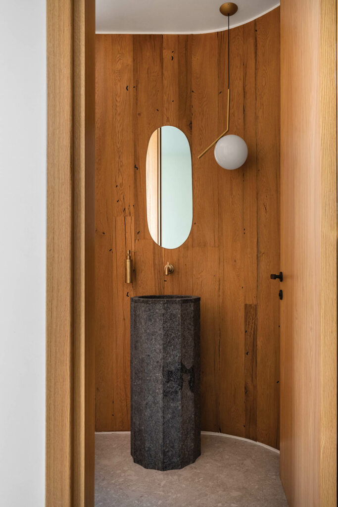 a wood panel wall in a bathroom with a gray pedestal sink