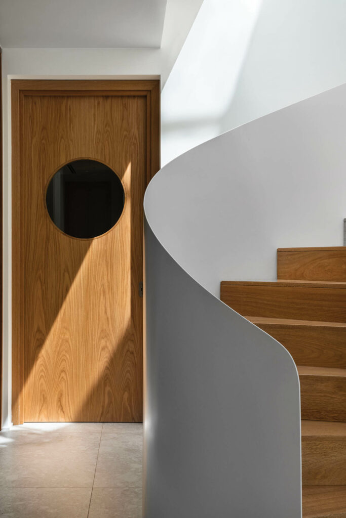 A porthole door be­tween the entry and the stair­case opens onto a hallway to the powder room.