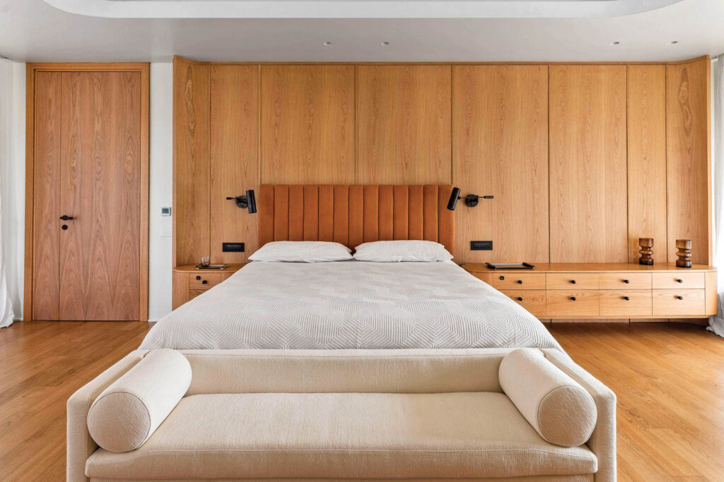 a linen headboard above a white bed in a room with wood panel walls