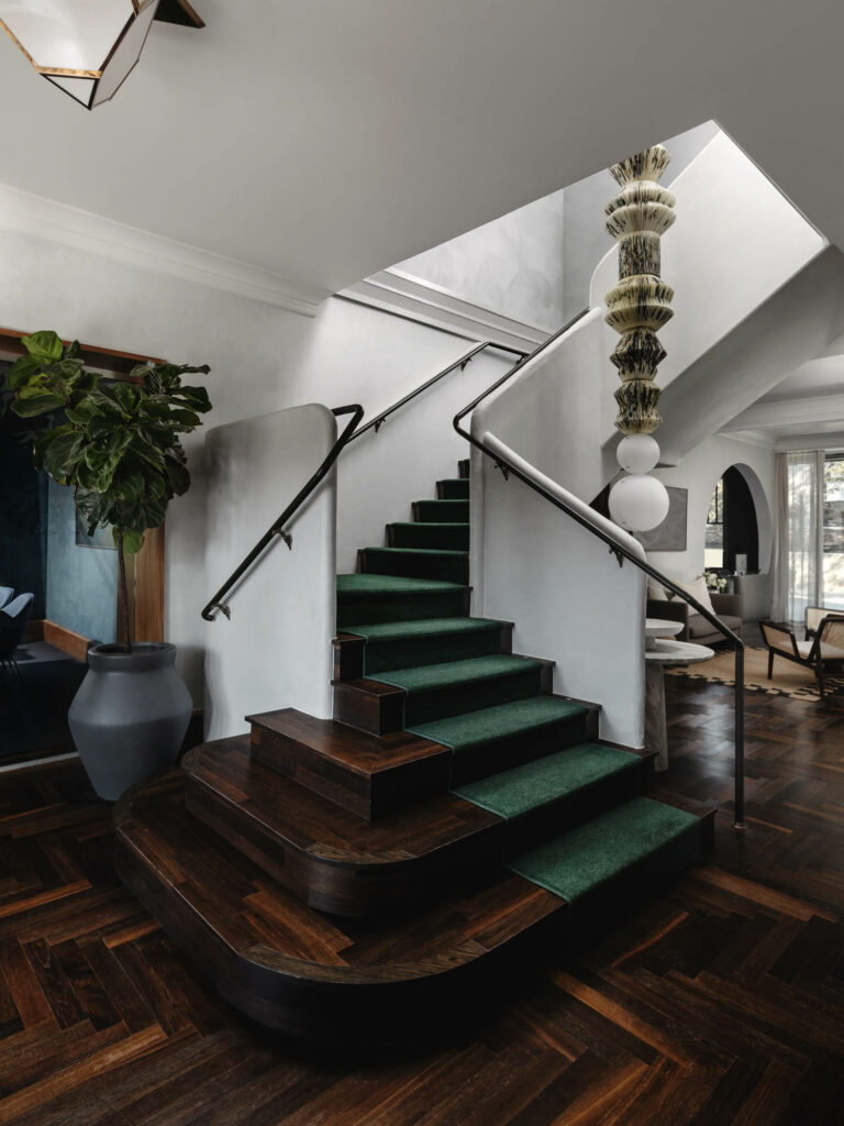 a curvilinear staircase with a green rug going up it