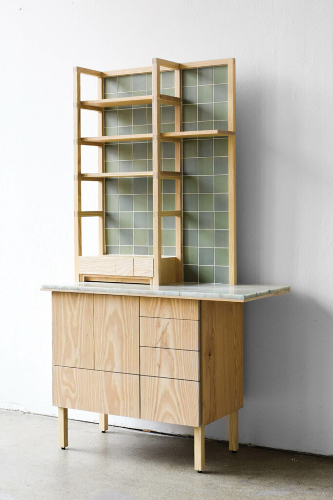 a wood bar with wood shelves above with green tile backing