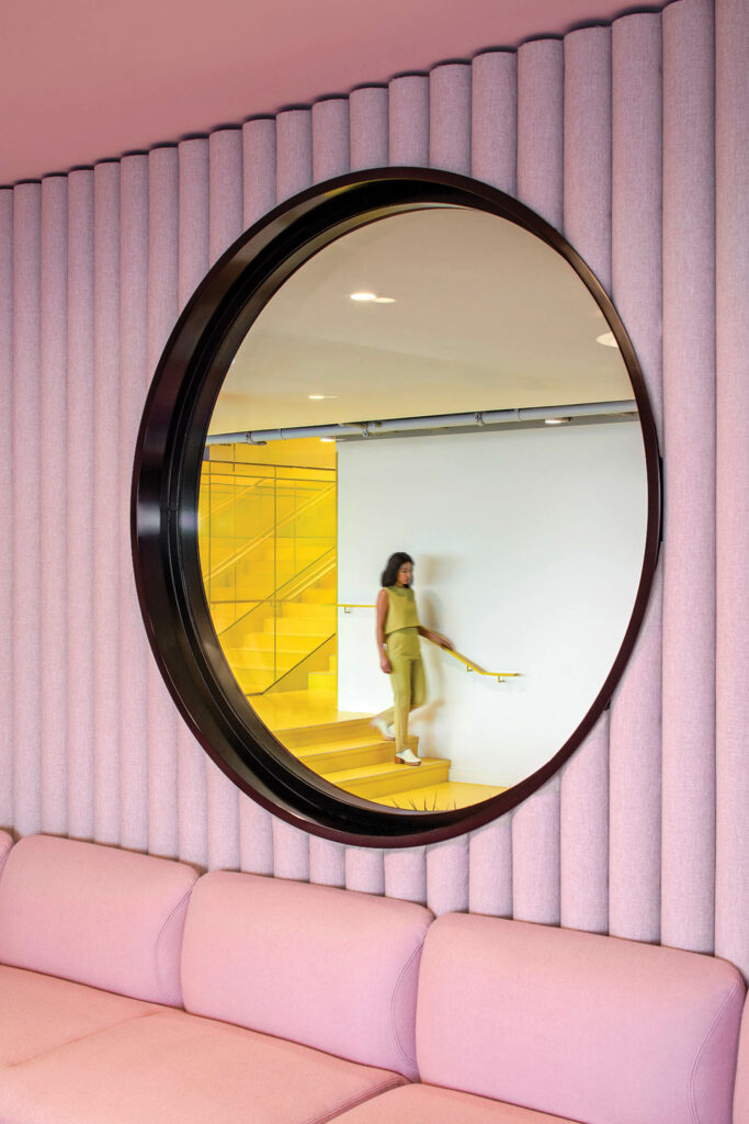 a textured pink wall with a circular window looks out to the staircase