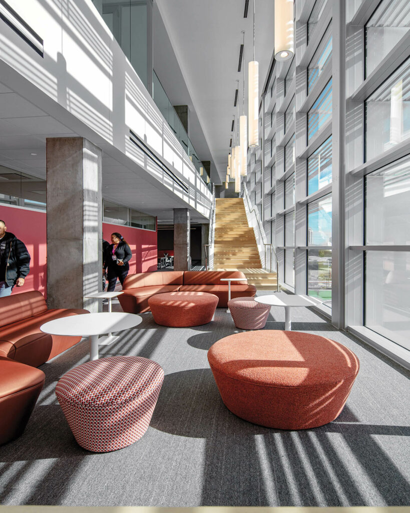 a common area with plush ottomans near a wall of windows