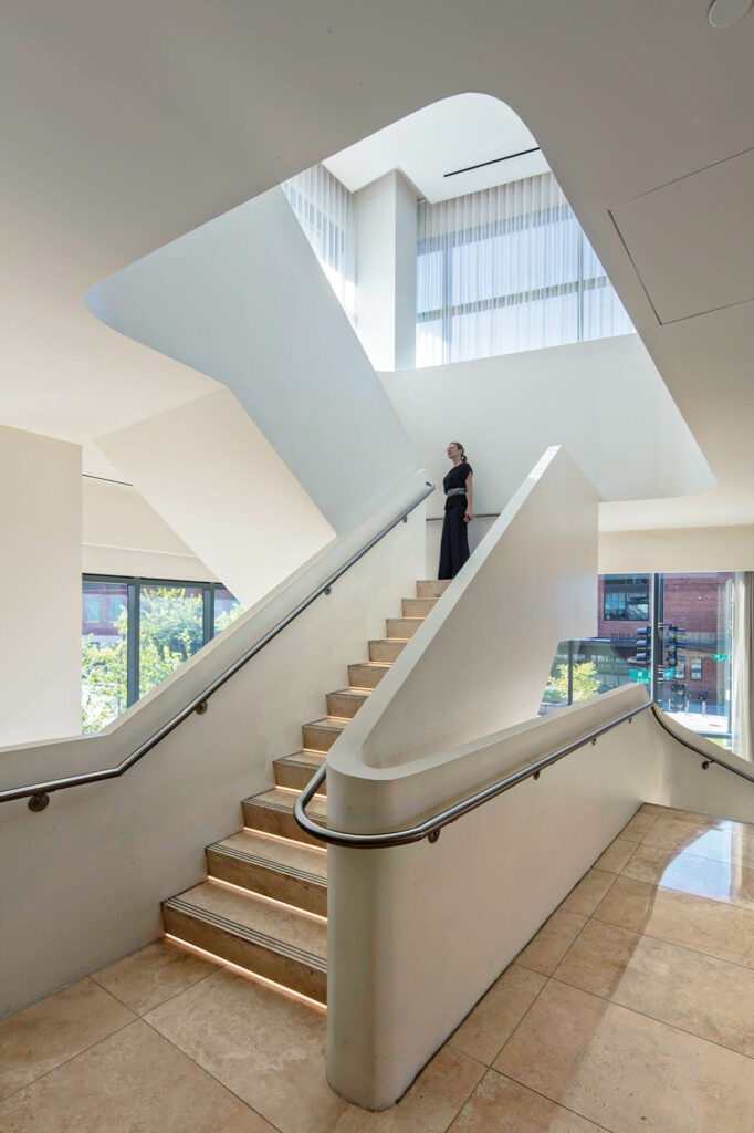 a woman stands at the top of the staircase at the Morrow Hotel