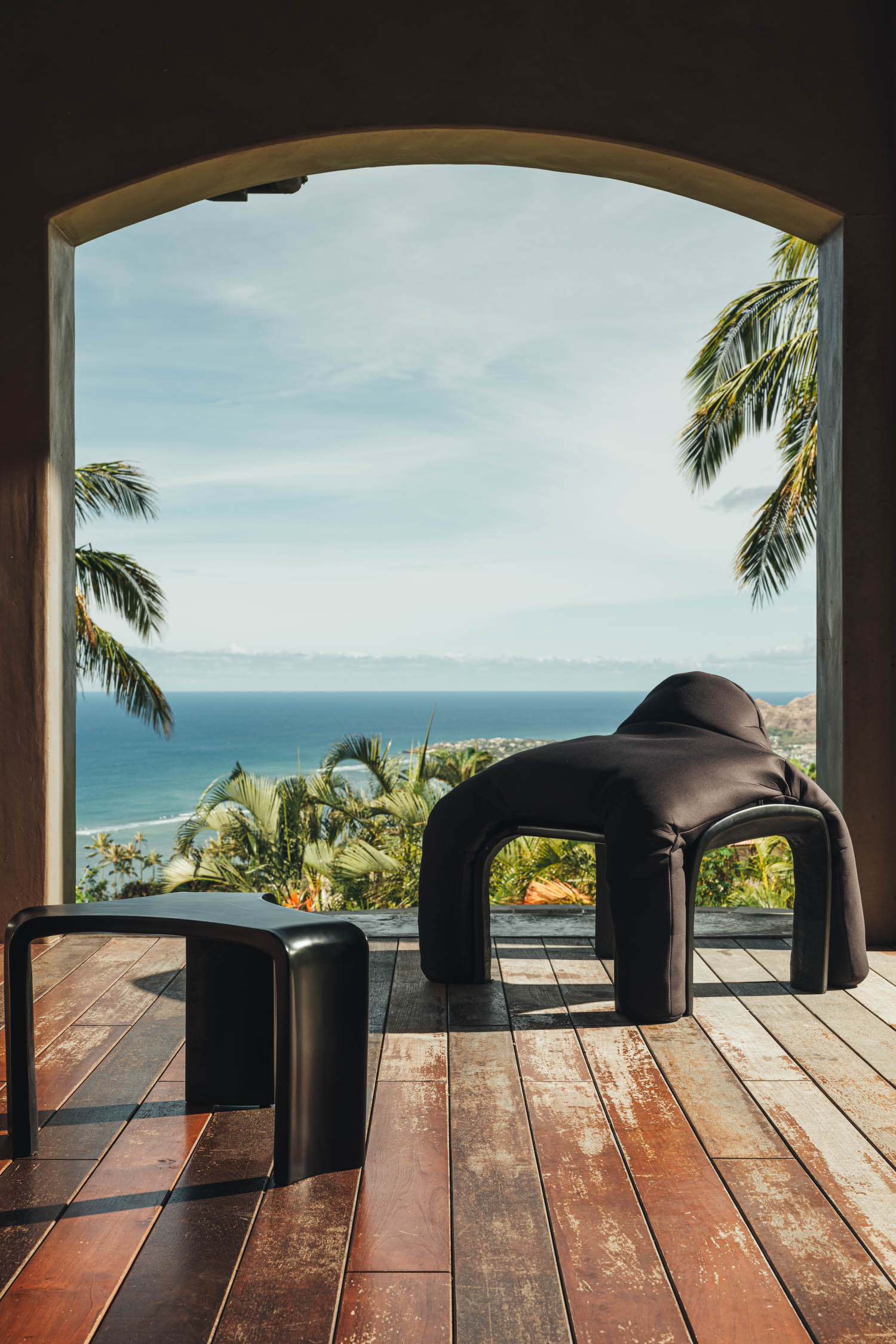 a curved armchair and stool on a patio