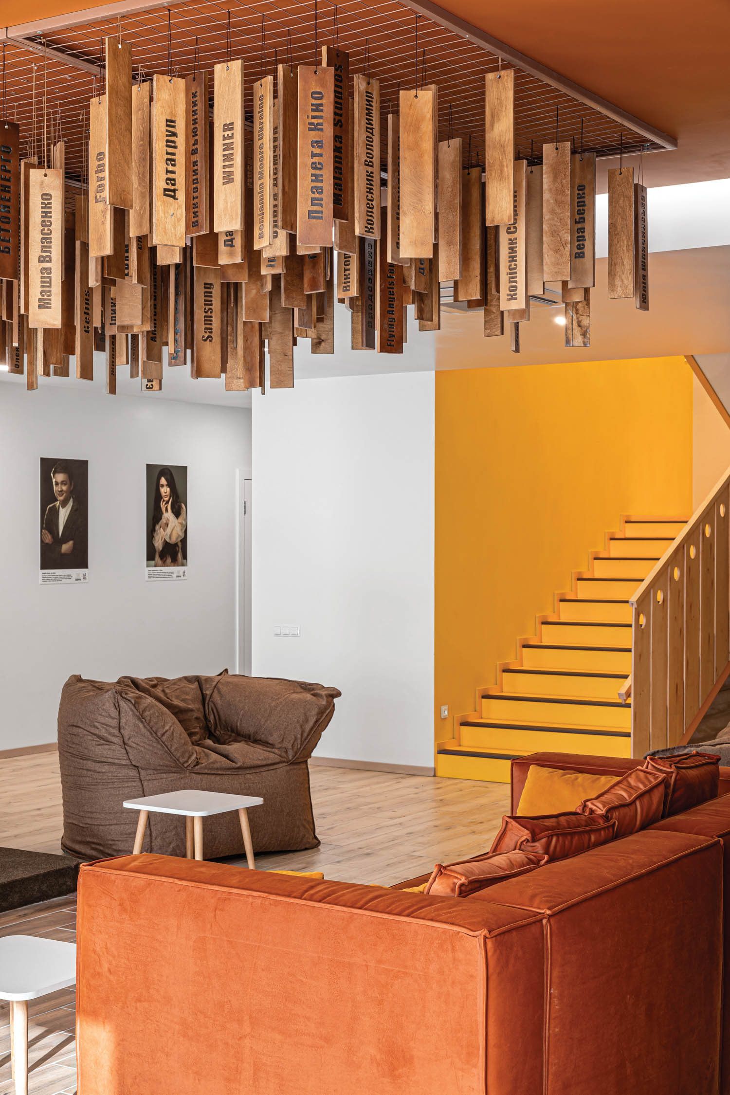 living room with brown chair, orange couch and multiple wooden sticks hanging from ceiling