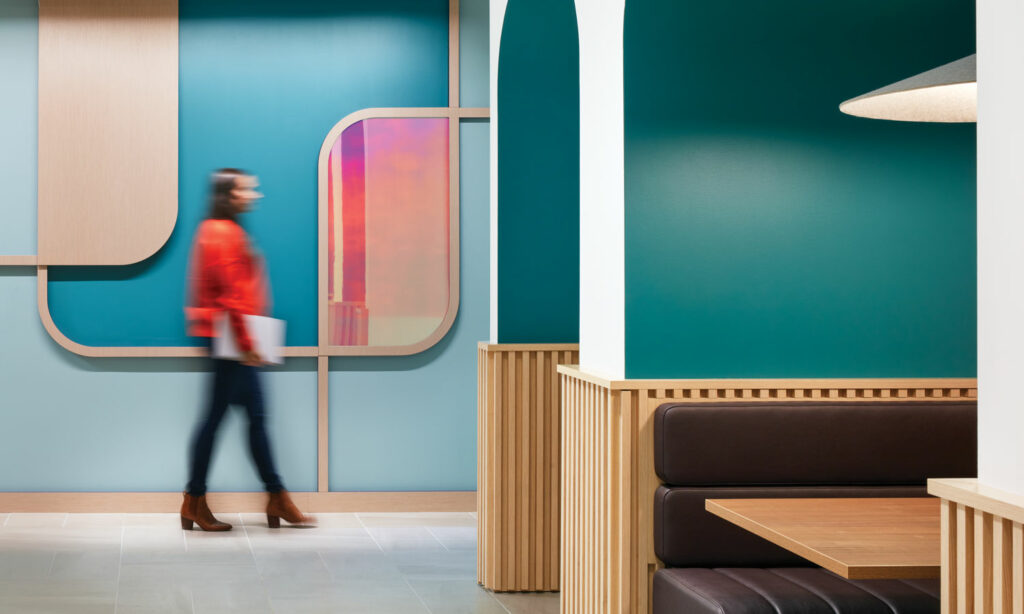 a woman walks through a colorful office with teal walls