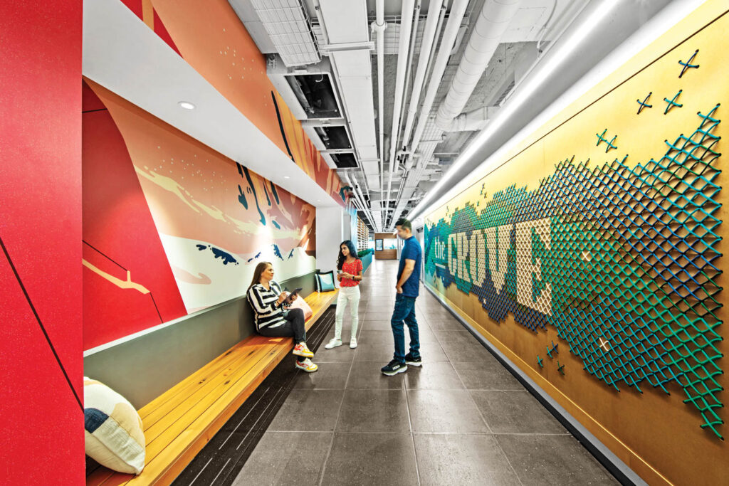 corridor hallway with an Auror Borealis mural on one side and a giant cross-stitch wall on the other