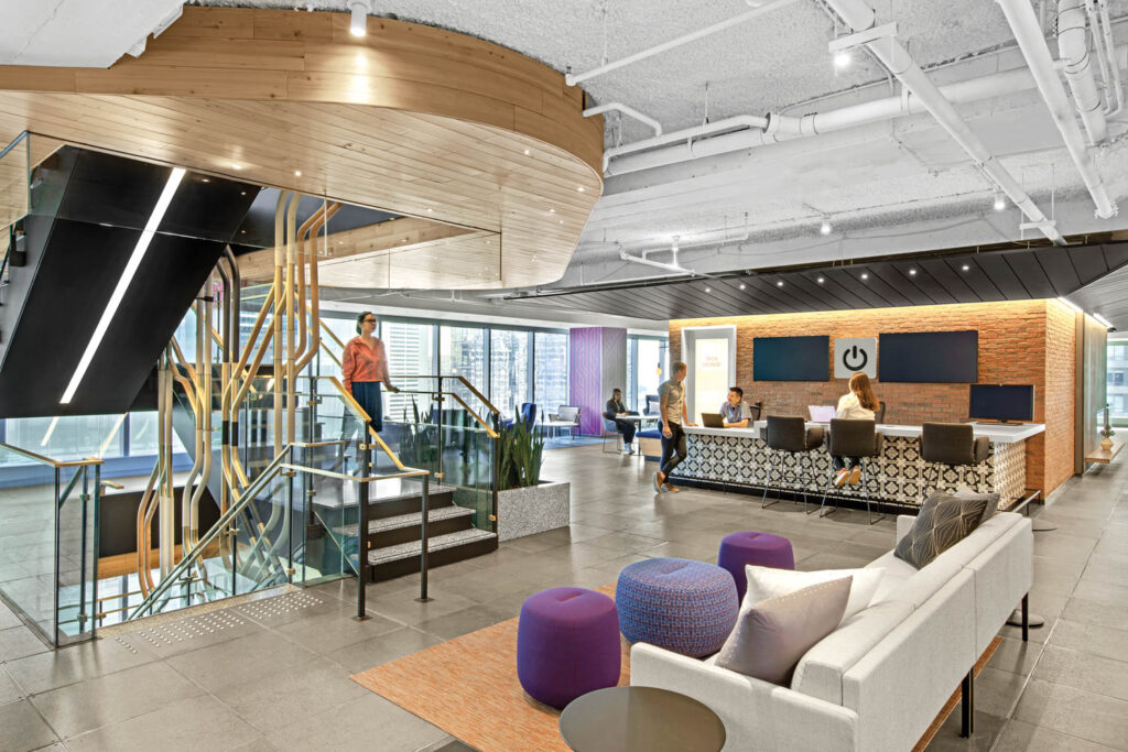 tech bar with nearby stairway, patterned reception desk and white sofa with purple ottomans