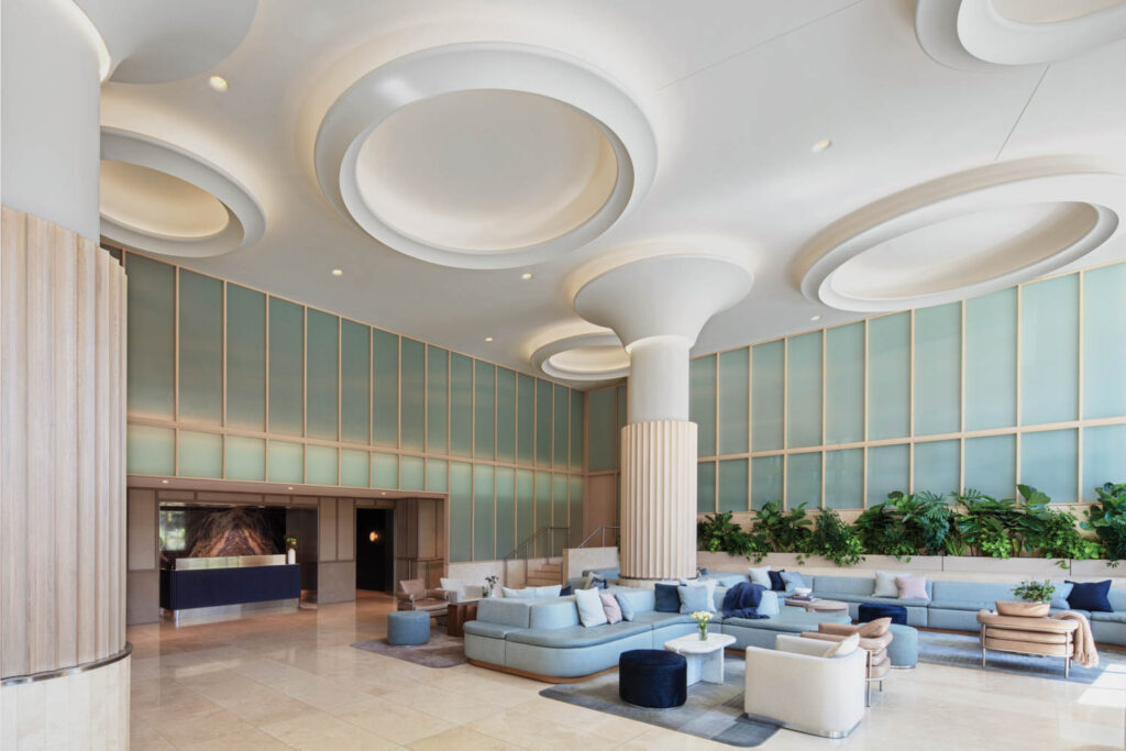 lobby of the Morrow Hotel with mint green glass panels along the walls and light blue settees