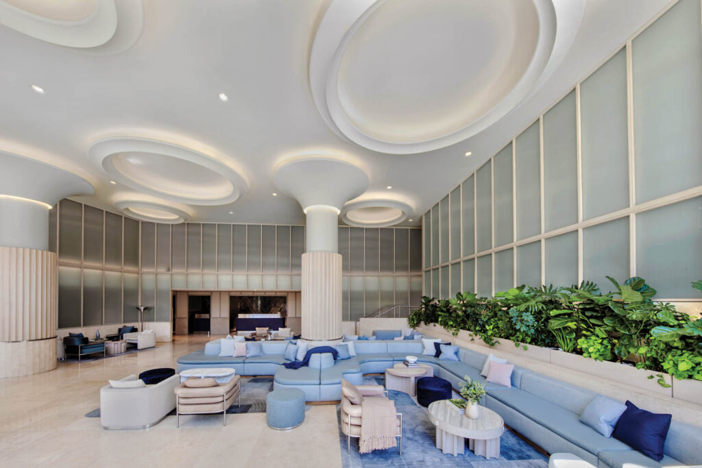 lobby of the Morrow Hotel with mint green glass panels along the walls and light blue settees