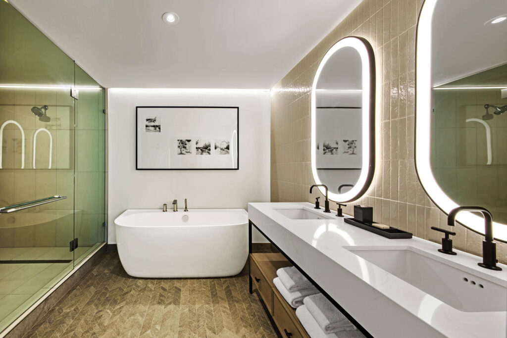 guest bathroom with limestone mosaic tiles, white bathtub and vanity