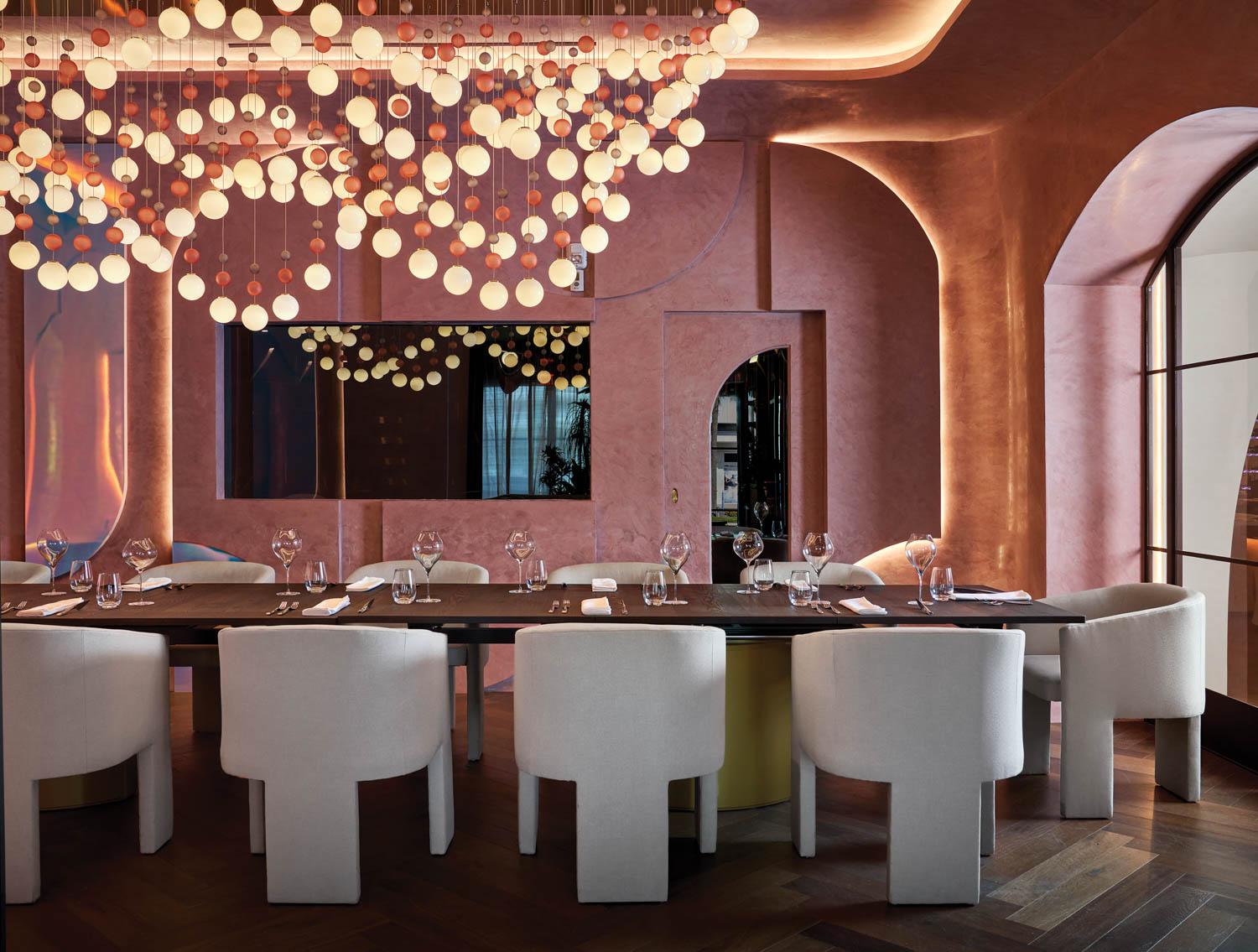 dining room with pink walls, long dining table and amorphous lights