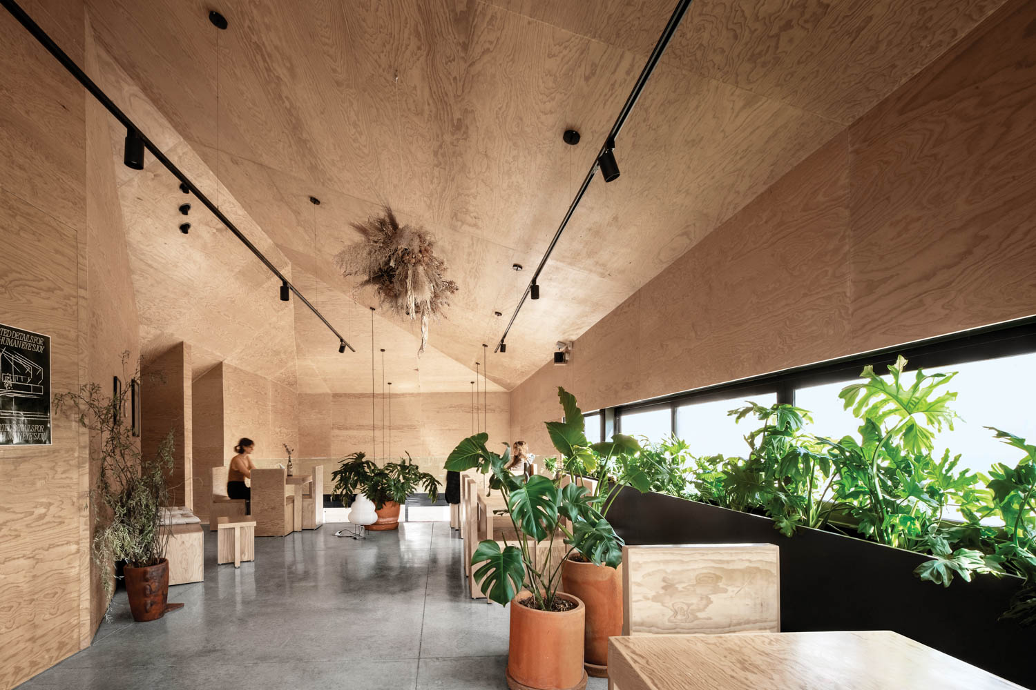 hallway area with high wooden ceilings, tables and lots of plants