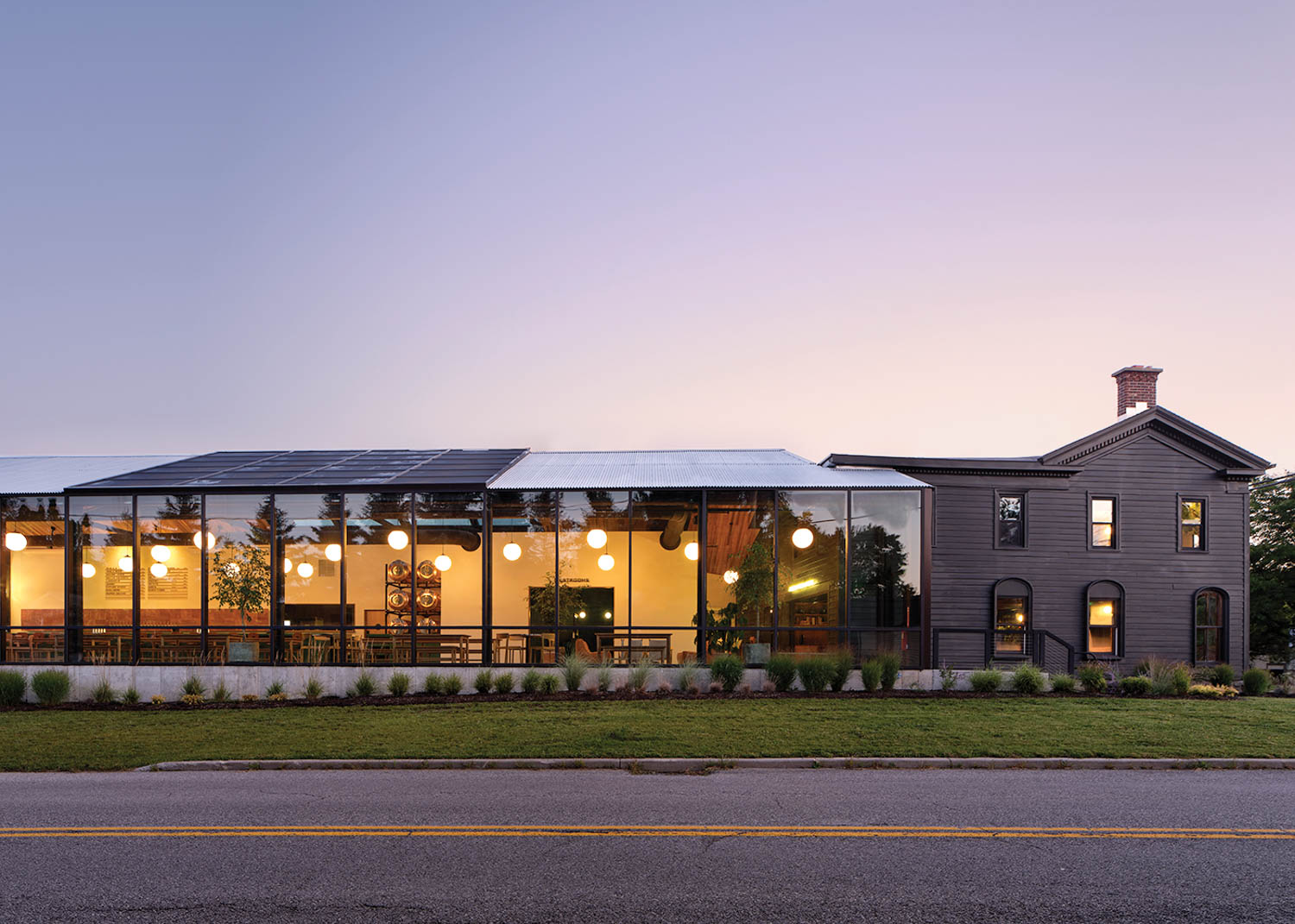 exterior facade of restaurant with bright lights and surrounding greenery