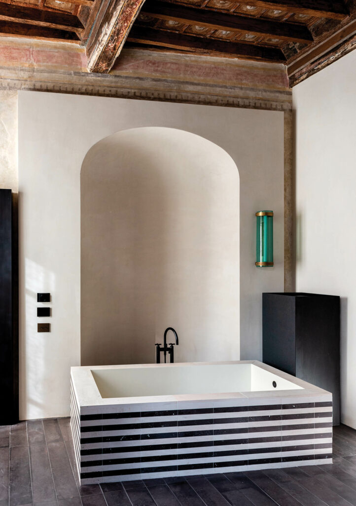 bathroom area with arched enclave and striped tub