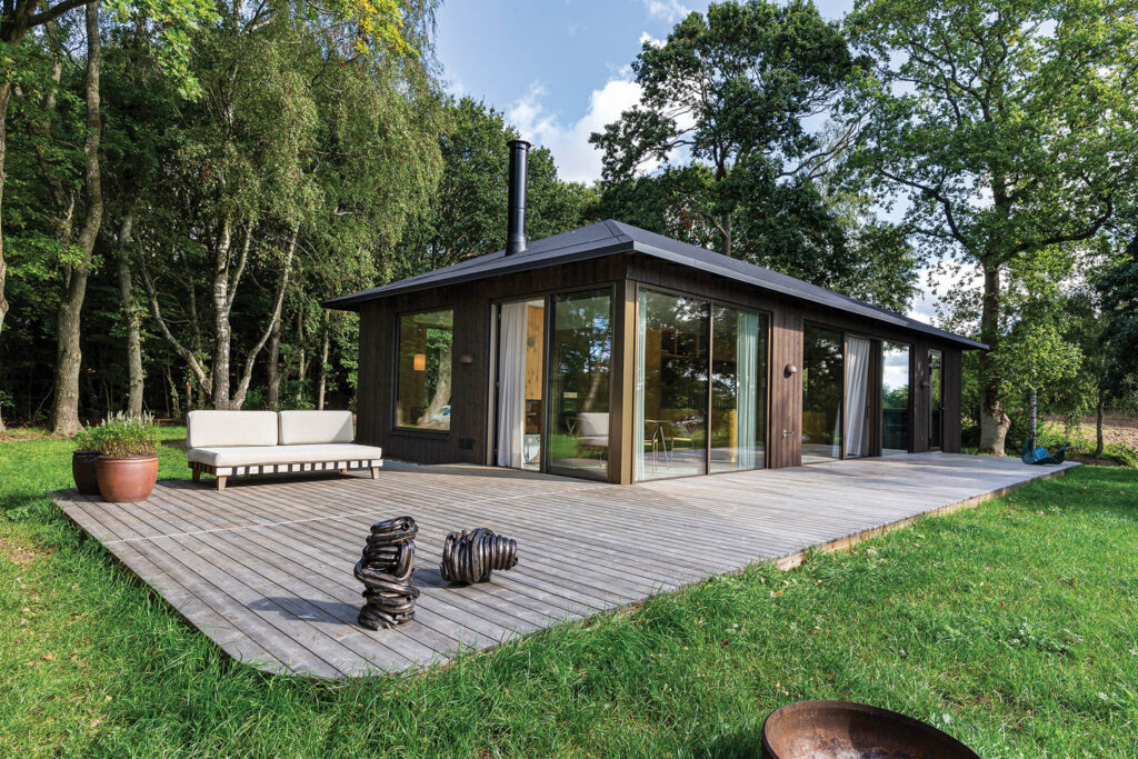 wooded home enclosed in glass next to a wooden deck