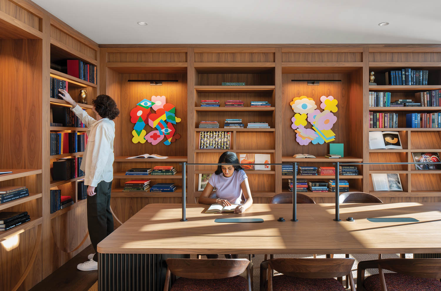 girl sitting in room with multiple shelves and at a long work table