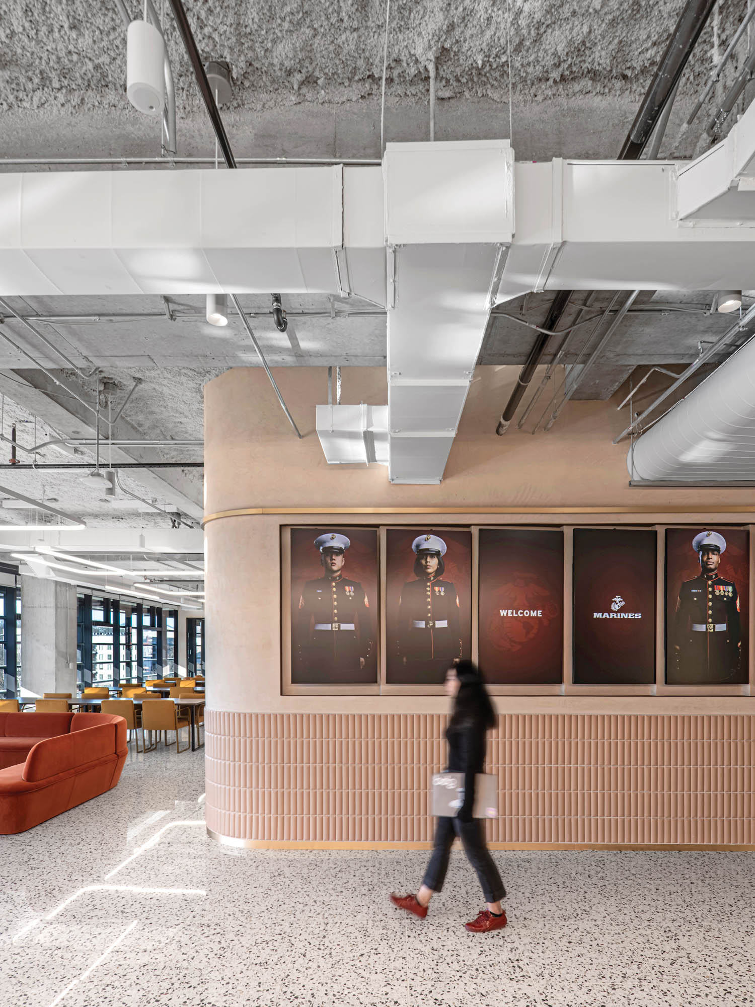 person walking through hallway with tall wooden walls and military posters