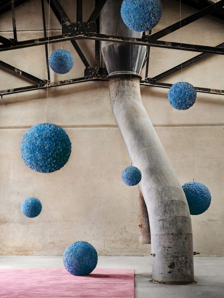 blue cloudlike balls in a room with a long tree trunk