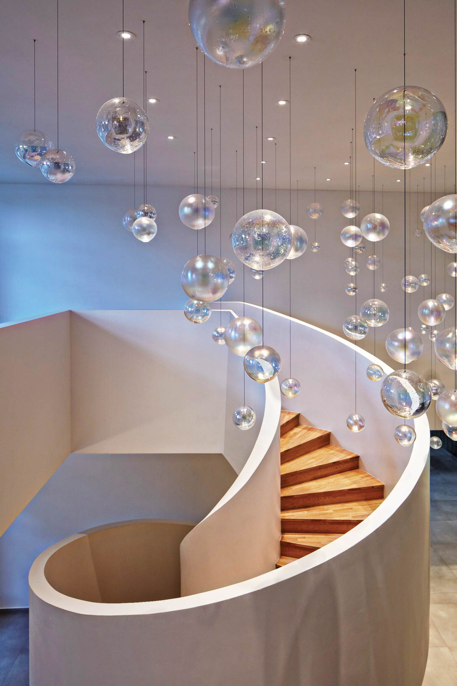 curved stairwell with hanging baubles from the ceiling and wooden steps