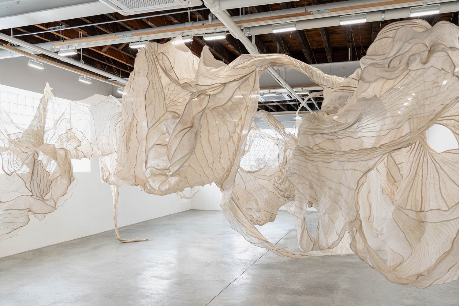 transparent textiles draped from the ceiling in the gallery