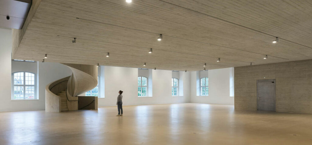 a woman gazing at the spiral staircase in a gallery