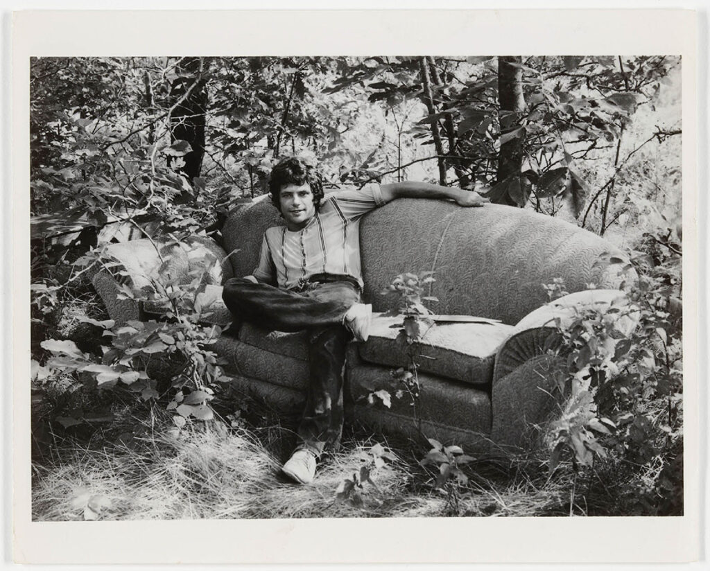 Scott Burton sitting on a couch in the woods