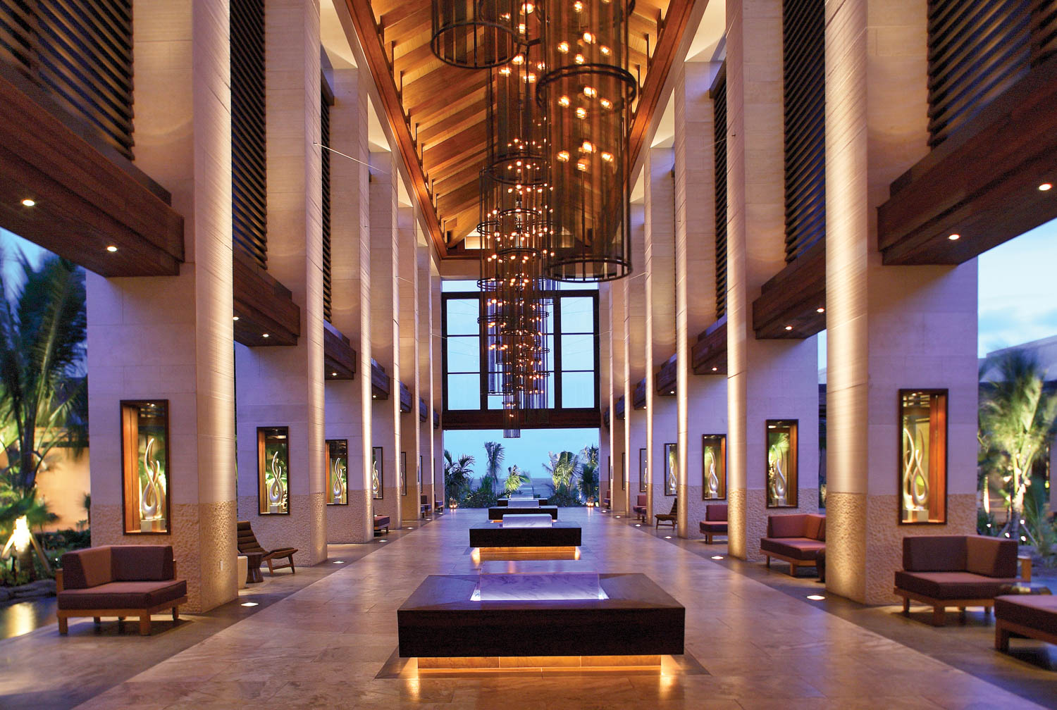 lobby area at night with seating, chandelier and open walls for indoor-outdoor space