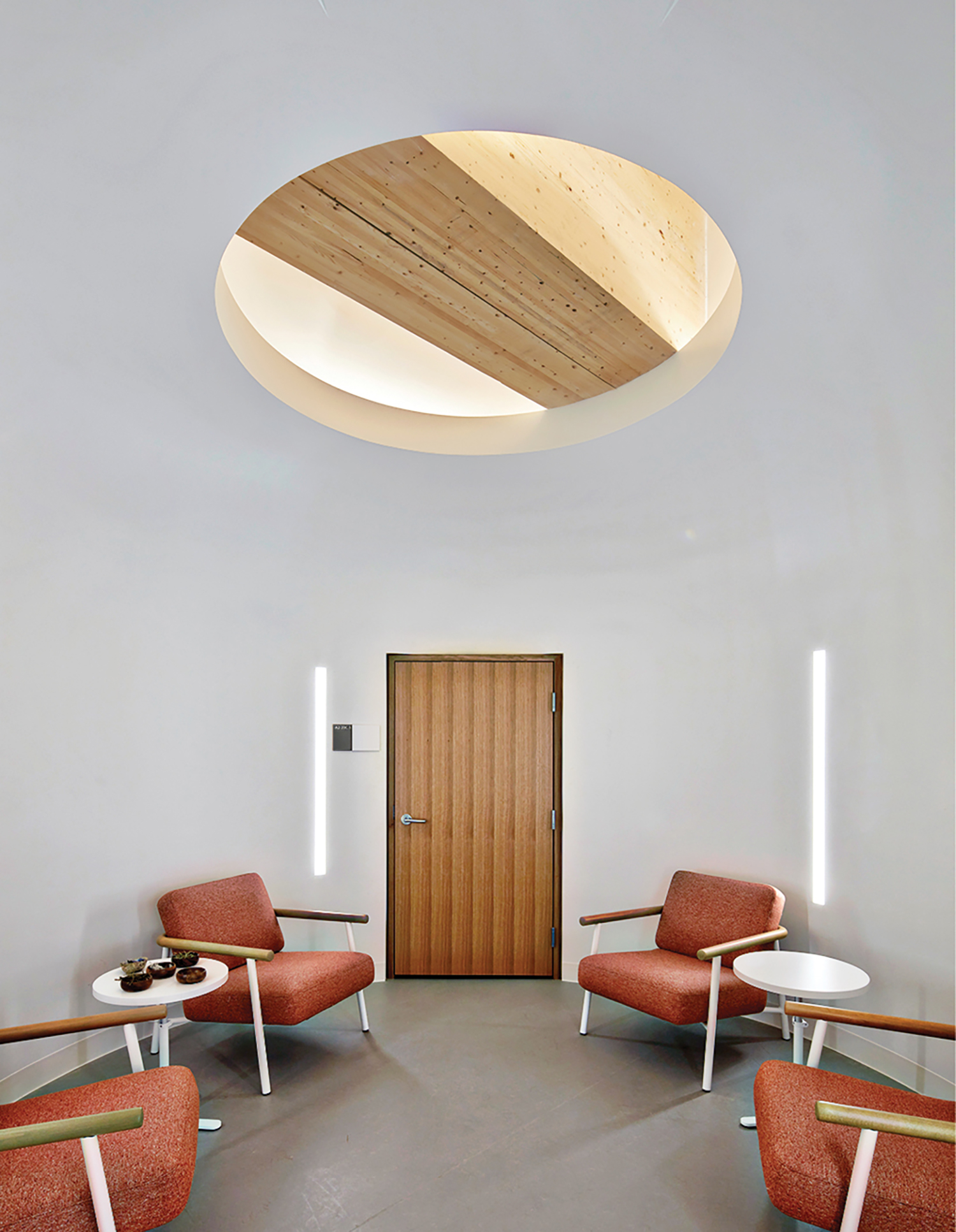 A room with a circular light above the chairs