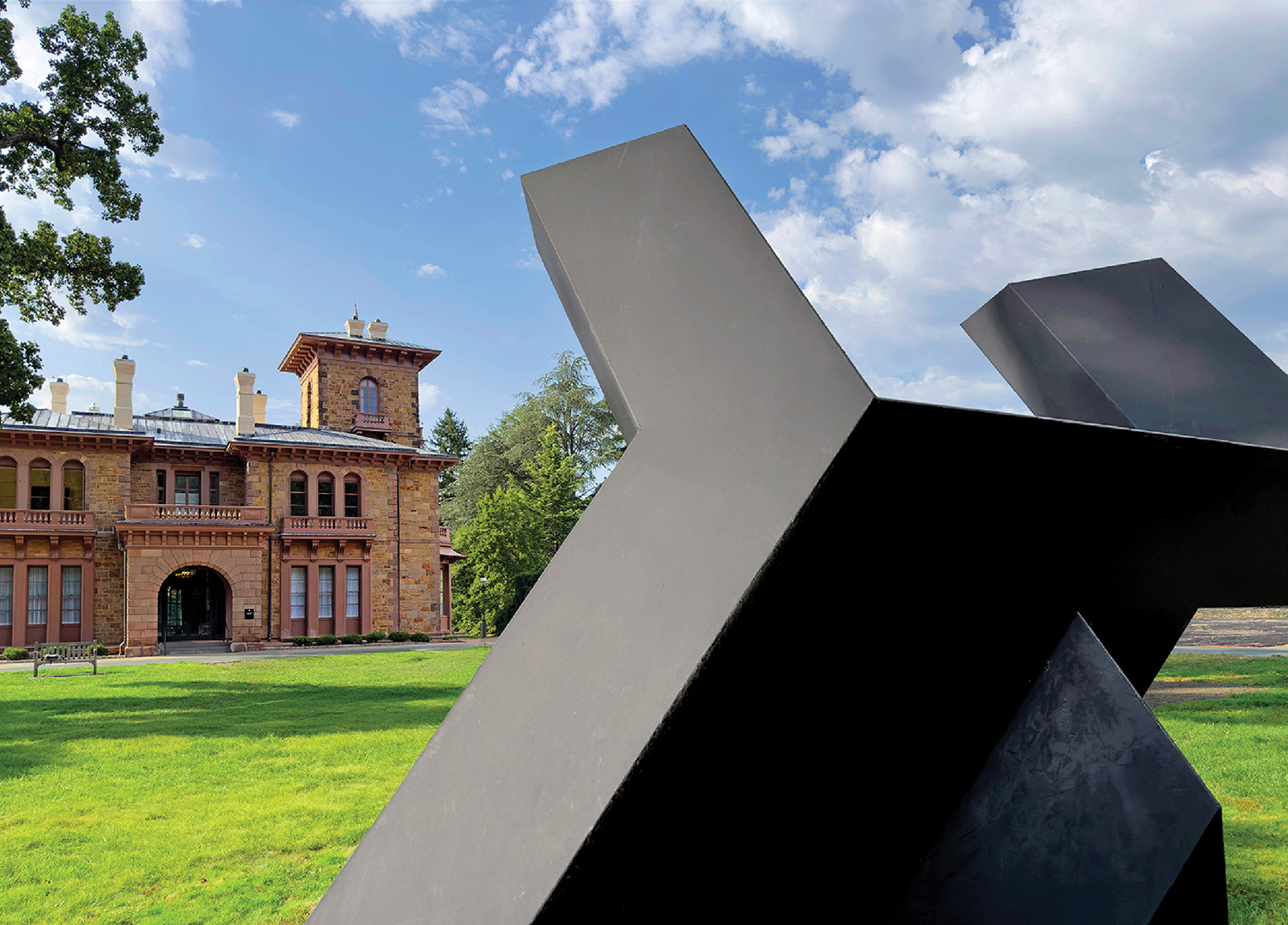 A sculpture in front of a building with a clock tower