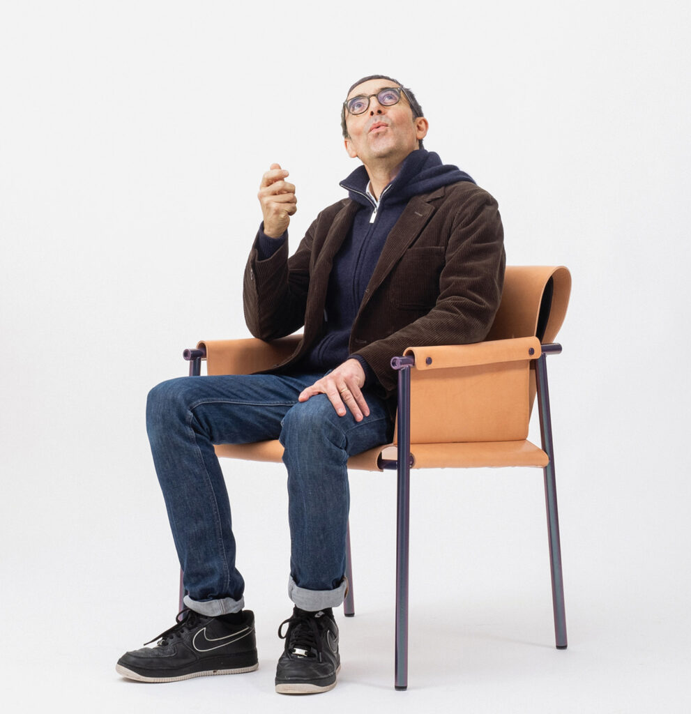 A man sitting on a chair smoking a cigarette