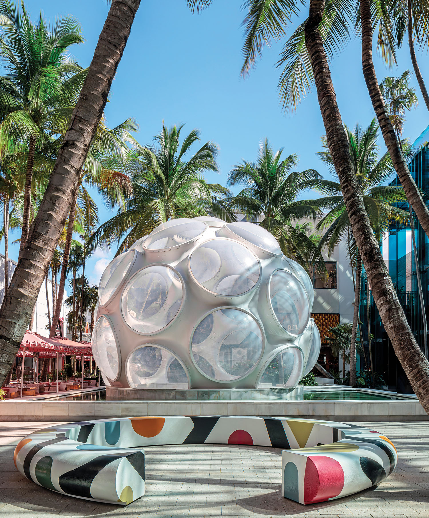 A large white sphere with colorful shapes on a concrete surface