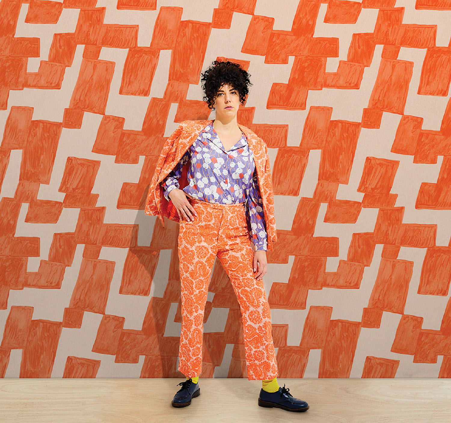 A woman in a colorful outfit standing in front of a wall