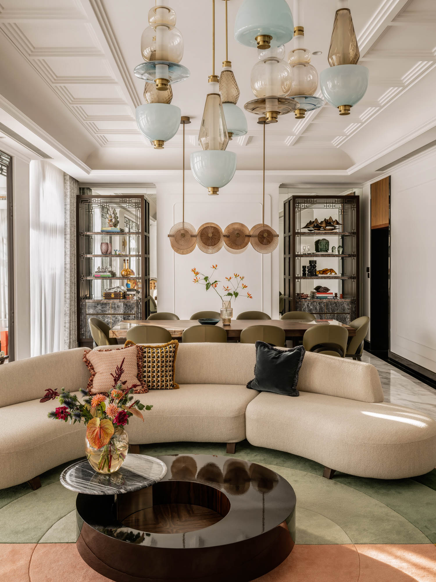 living room with curved white couch and view of the dining area with chandeliers