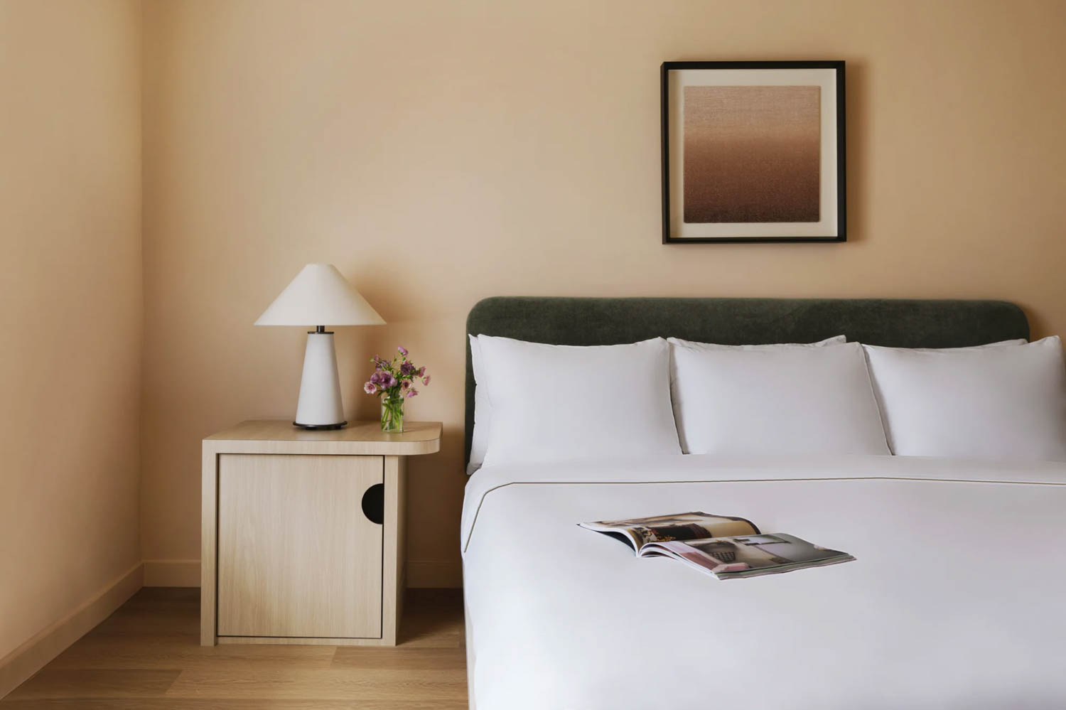corner of room with big white bed and side console